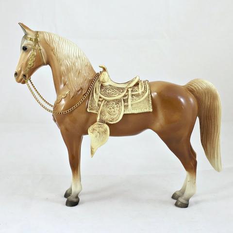 #57 Wester Horse produced by Breyer in 1950. The horse is light brown with a gold colored western saddle and bridle. It is being viewed to the side with the horse facing left.