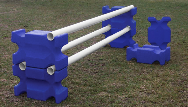 Blue jump blocks are stacked one on top of the other on either side with white poles in the middle to make a jump.
